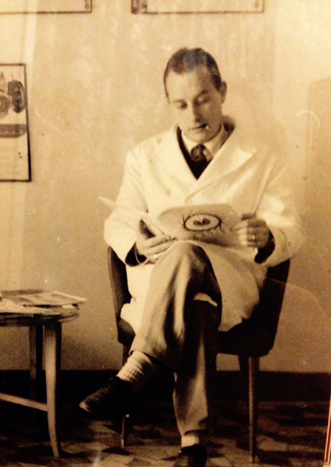 Il nonno seduto in camice bianco, con in mano una tavola anatomica dell occhio